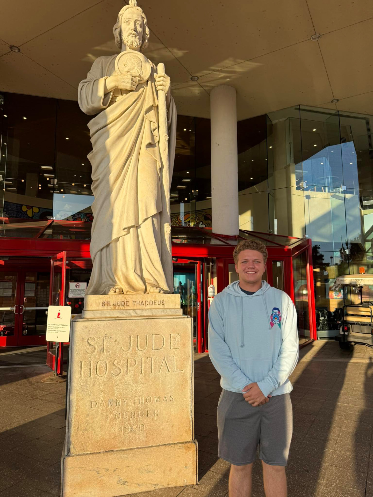 Caden standing beside the St. Jude Thaddeus statue at St. Jude Children's Hospital